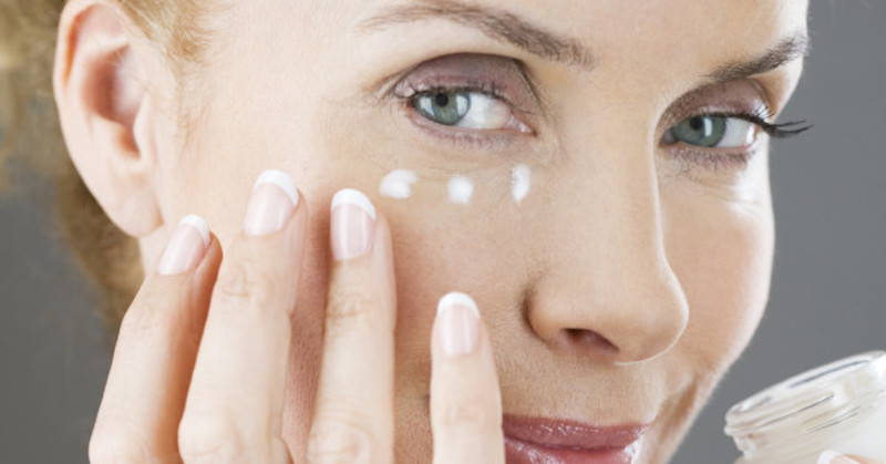 woman applying cream on wrinkles