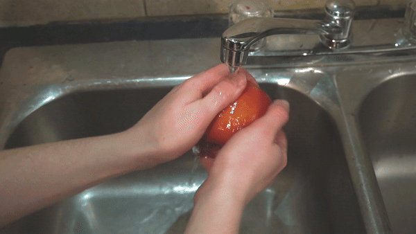 hands washing apple in sink